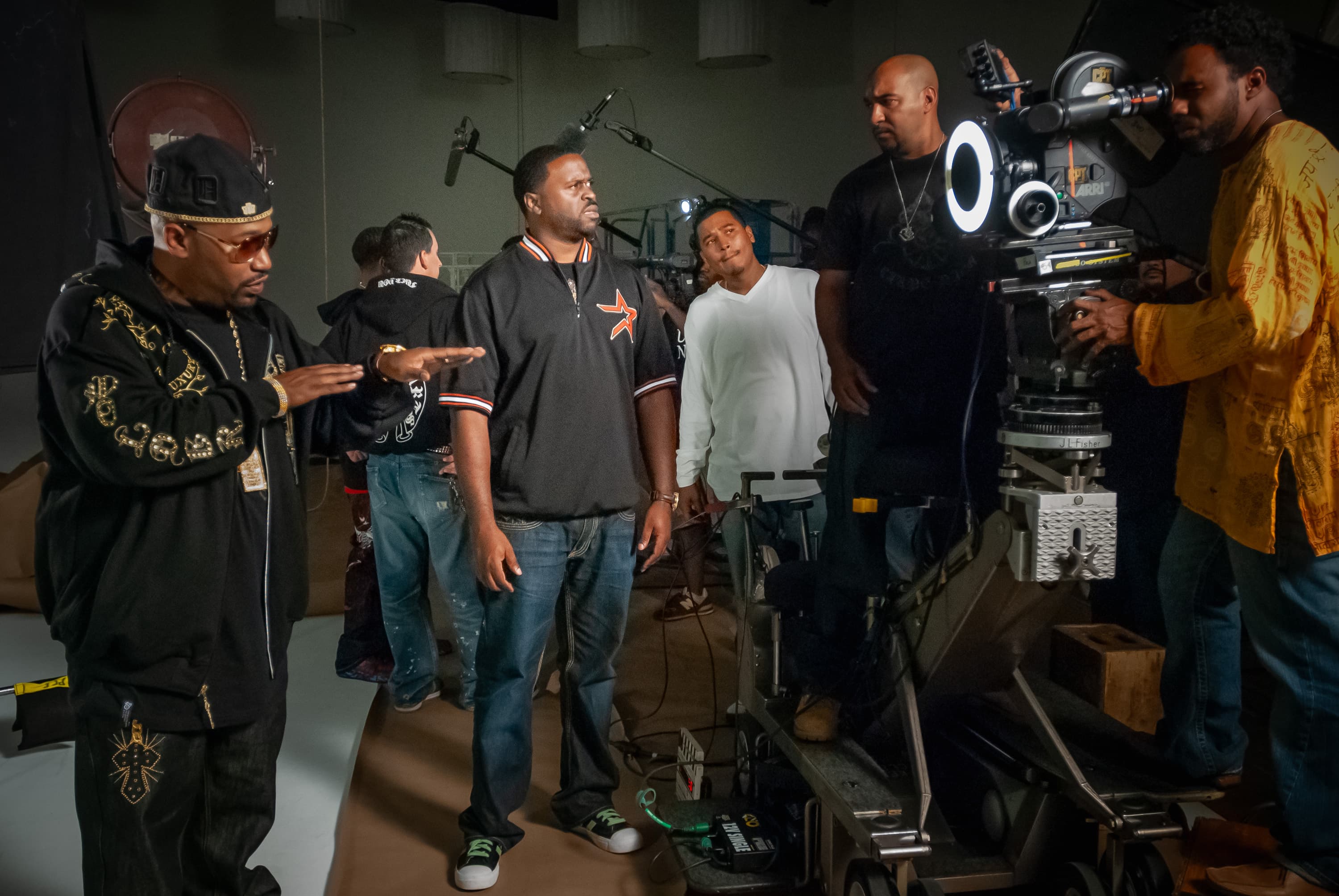 A movie camera on a dolly is focused on a closeup of rapper Bun B, with the crew standing around the camera.