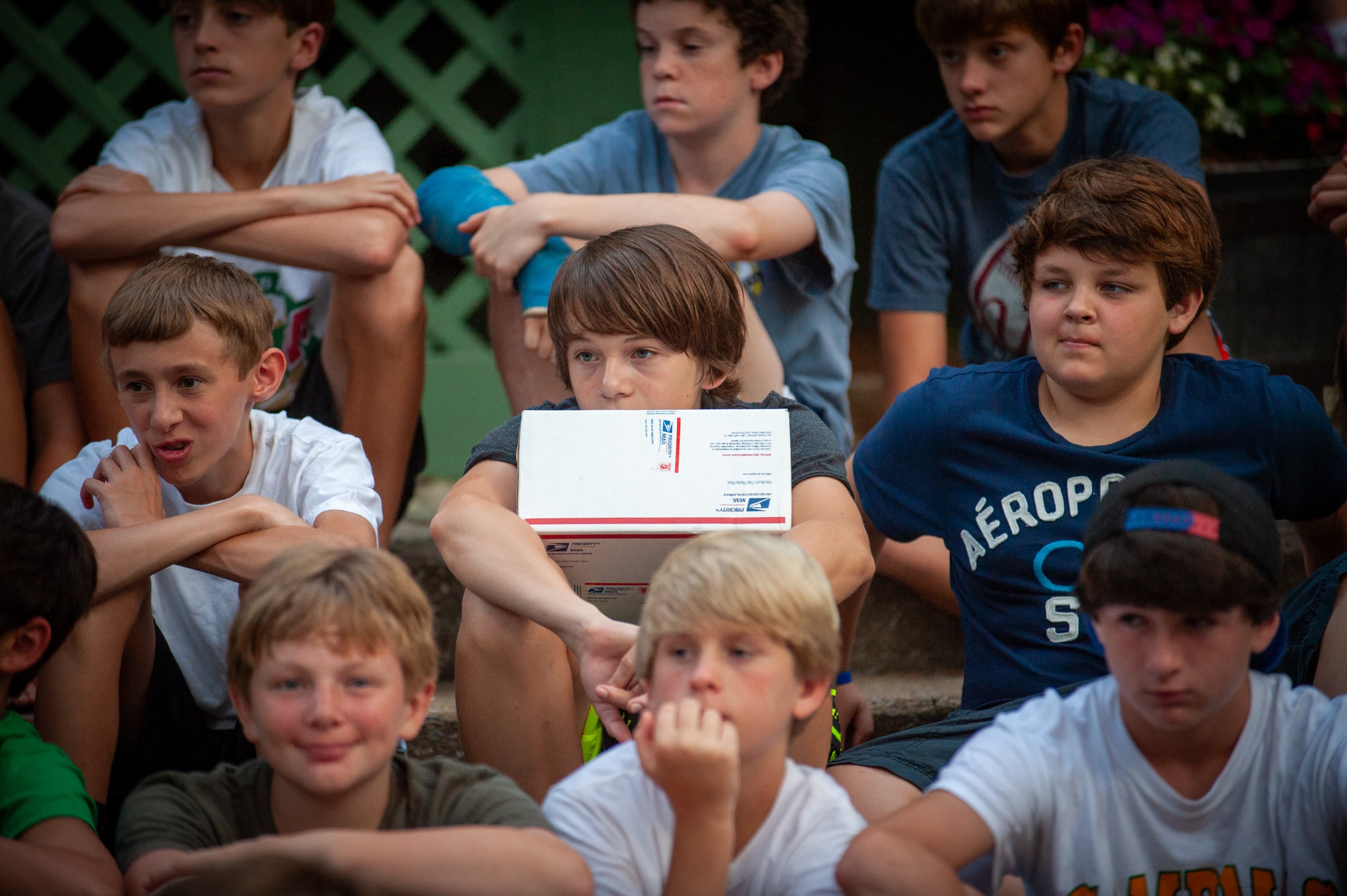 A group of boys sitting on steps, with one holding a USPS box.